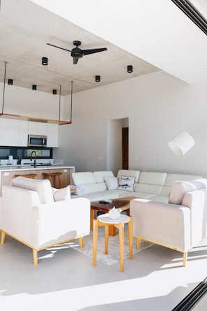 Una sala de estar moderna con un sofá, una mesa de centro y una zona de cocina con un microondas.
