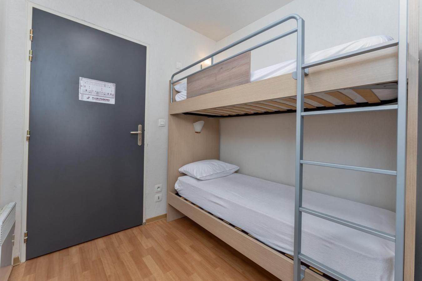 A bunk bed room with a dark door, a light switch, and a Plan Parking sign.