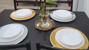 Una mesa de comedor dispuesta con platos blancos y detalles dorados, rodeada por dos sillones color beige.
