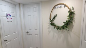 Un pasillo con puertas blancas, una felpudo y una corona en la pared.