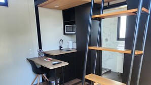 A compact studio apartment with a bunk bed, kitchenette, and a small dining area. - Enchanting Tiny Home in Vibrant Dickson (Dickson)