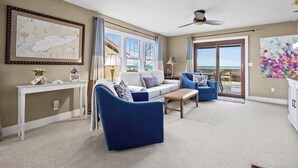 A spacious living room with a large window, a ceiling fan, and a view of the outdoors.