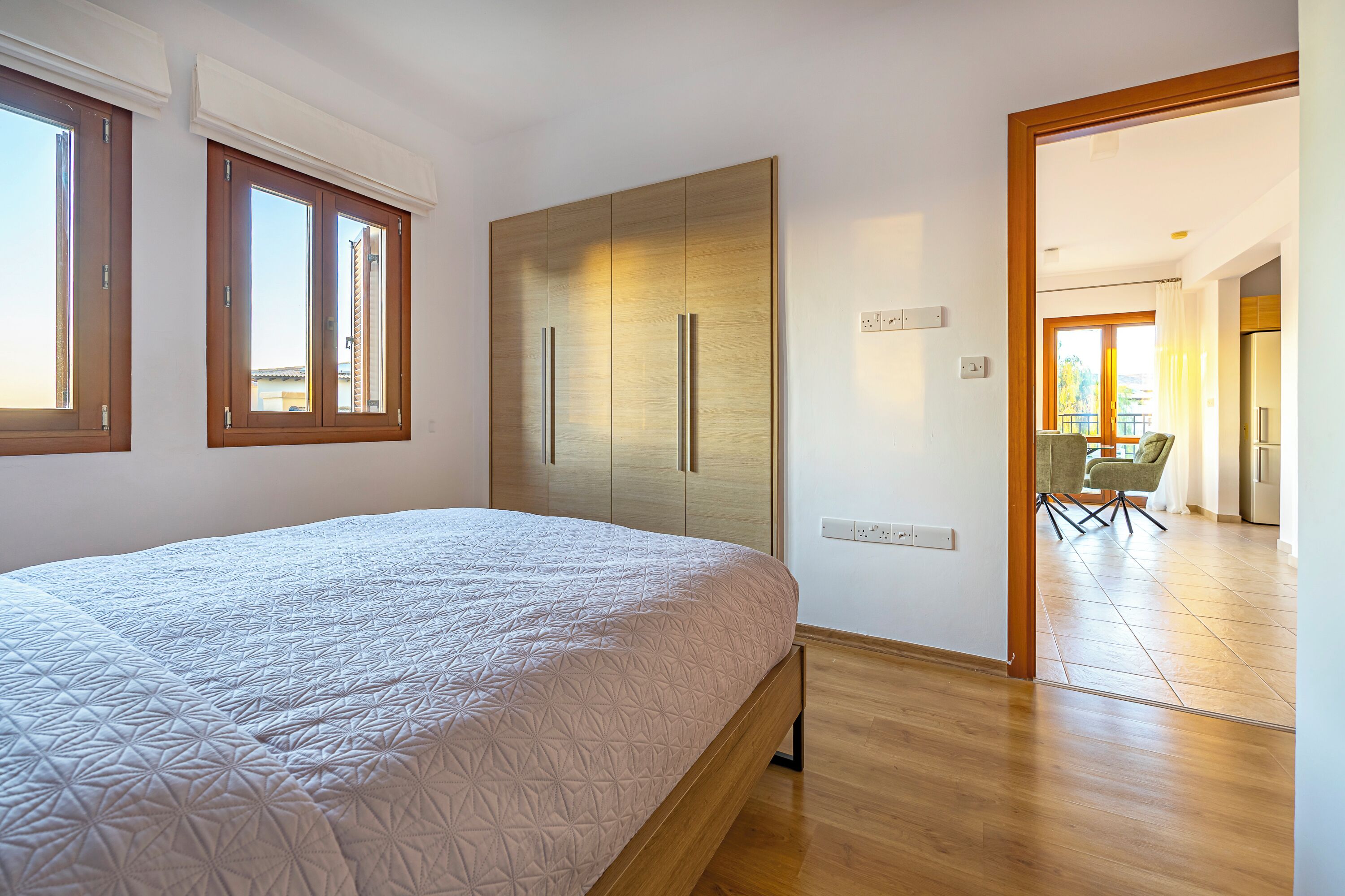 A bedroom with a bed, wardrobe, and a view of the outside.