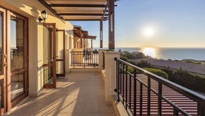 Un balcón con vista al mar, una pérgola y una barandilla.
