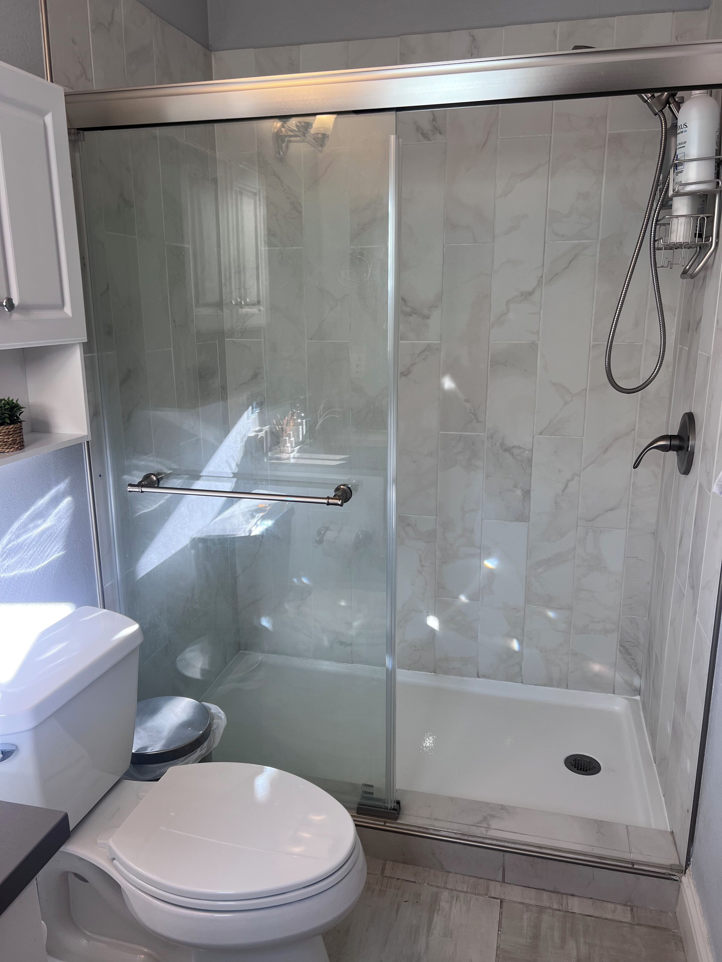A modern bathroom with a glass-enclosed shower, a toilet, and a sink.
