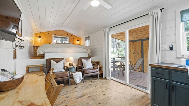 A cozy cabin-style room with a wooden ceiling, a large bed, a dining table, and a kitchen area. - The Golden Nugget Cabin (Keystone)
