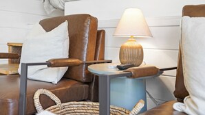 A brown leather sofa with a white pillow and a small table with a lamp. - The Golden Nugget Cabin (Keystone)