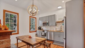 Una cocina moderna con armarios grises, electrodomésticos de acero inoxidable y una mesa de comedor de madera.