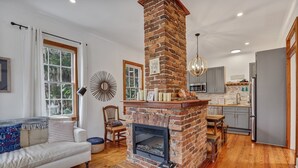 Una sala de estar con chimenea, un sofá, una mesa de comedor y una zona de cocina con electrodomésticos modernos.