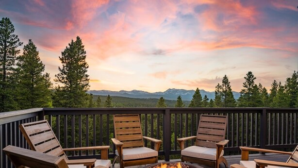 A deck with wooden chairs and a fire pit, overlooking a forest and mountains. - Serene Retreat Amazing Views Hottub Sauna Xbox (Black Hawk)