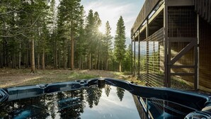 A hot tub with a view of a forest and a building with a balcony. - Serene Retreat Amazing Views Hottub Sauna Xbox (Black Hawk)