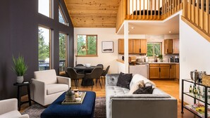 A modern living room with a sofa, armchairs, and a dining area. A kitchen is visible in the background. - Serene Retreat Amazing Views Hottub Sauna Xbox (Black Hawk)