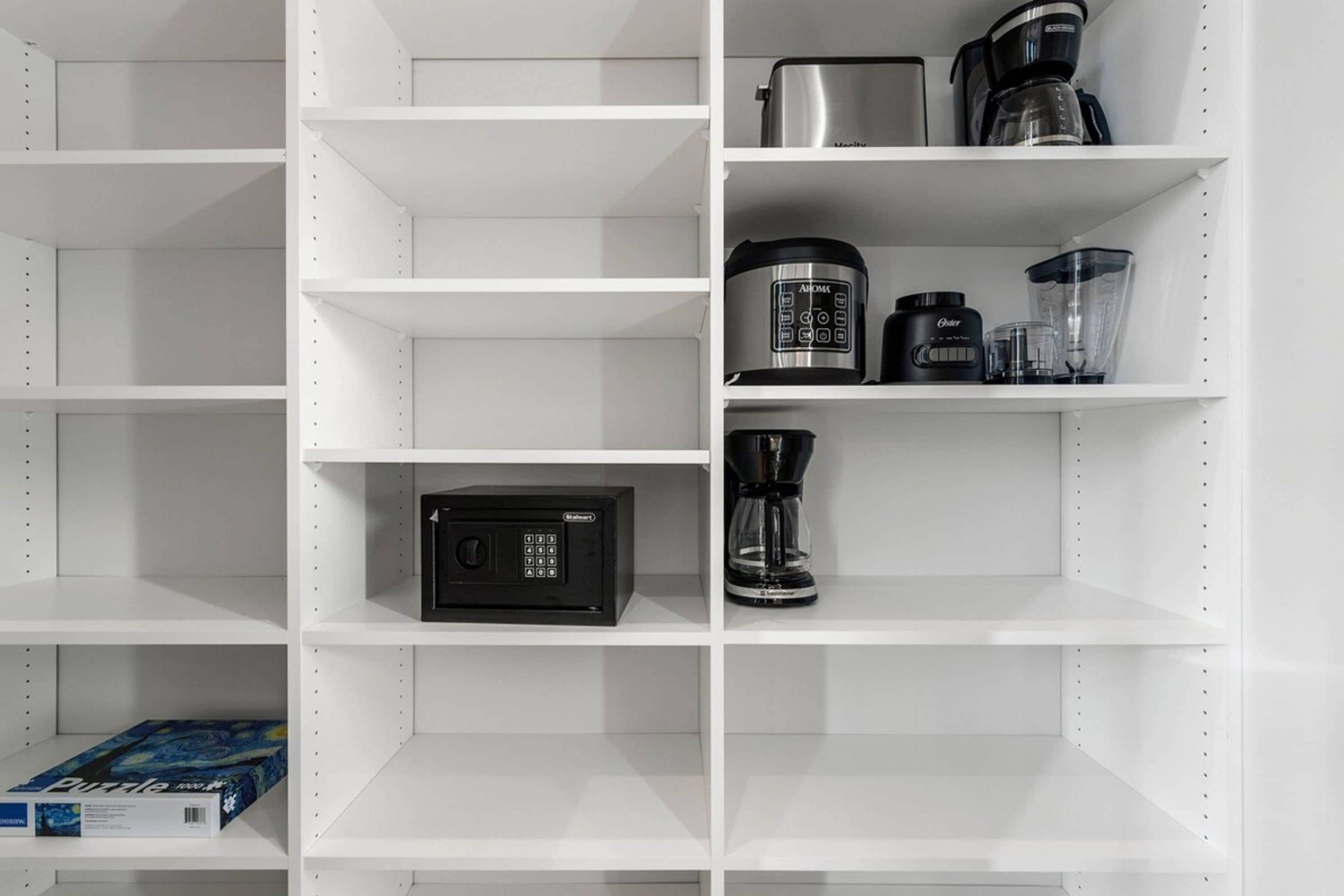 A kitchen with white shelves, a microwave, a coffee maker, and a blender.