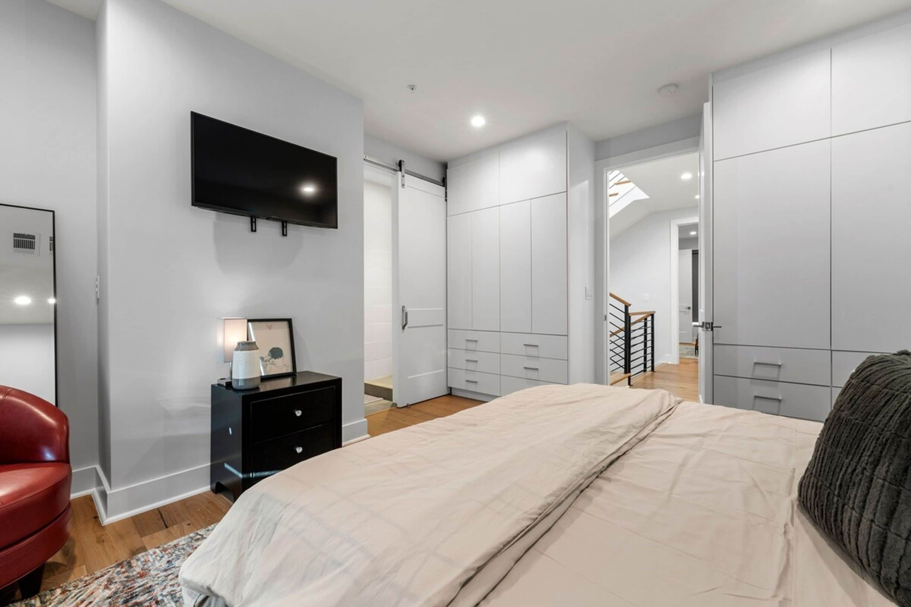 Una camera da letto con un letto, una TV a parete, un comò e un armadio.