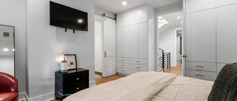 Una camera da letto con un letto, una TV a parete, un comò e un armadio.