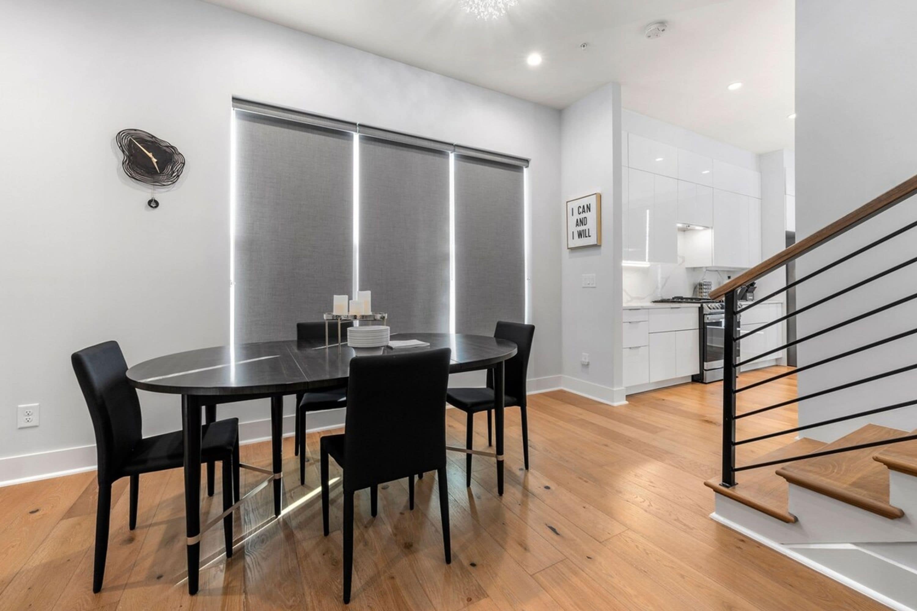 Une cuisine moderne avec des meubles blancs, un réfrigérateur en acier inoxydable et un escalier en bois.