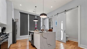 A modern kitchen with a central island, stainless steel appliances, and pendant lighting.