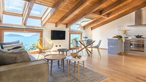 Amplia sala de estar con techo de madera, televisor grande y vista al mar.