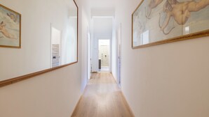 A hallway with wooden flooring, white walls, and framed artwork on the walls. - Ostiensis Place, cozy accommodation in the heart of Rome, 9 minutes from metro B (Roma)
