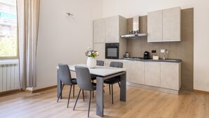 A modern kitchen with a dining area, featuring a built-in oven, microwave, and a large cabinet above the counter. - Ostiensis Place, cozy accommodation in the heart of Rome, 9 minutes from metro B (Roma)