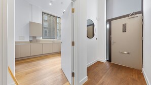 A modern hotel room with a wooden floor, a large window, a mirror, and a door with a sign. - Split Level Apartment (London)