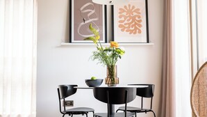 Un coin repas avec une table ronde, des chaises noires et un vase rempli de fleurs.