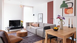 Un salon moderne comprenant un canapé, un téléviseur et un coin repas avec une table et des chaises.
