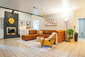 Ein modernes Wohnzimmer mit einem Ecksofa, einem gelben Sessel, einem Kamin und einer großen Wanduhr.