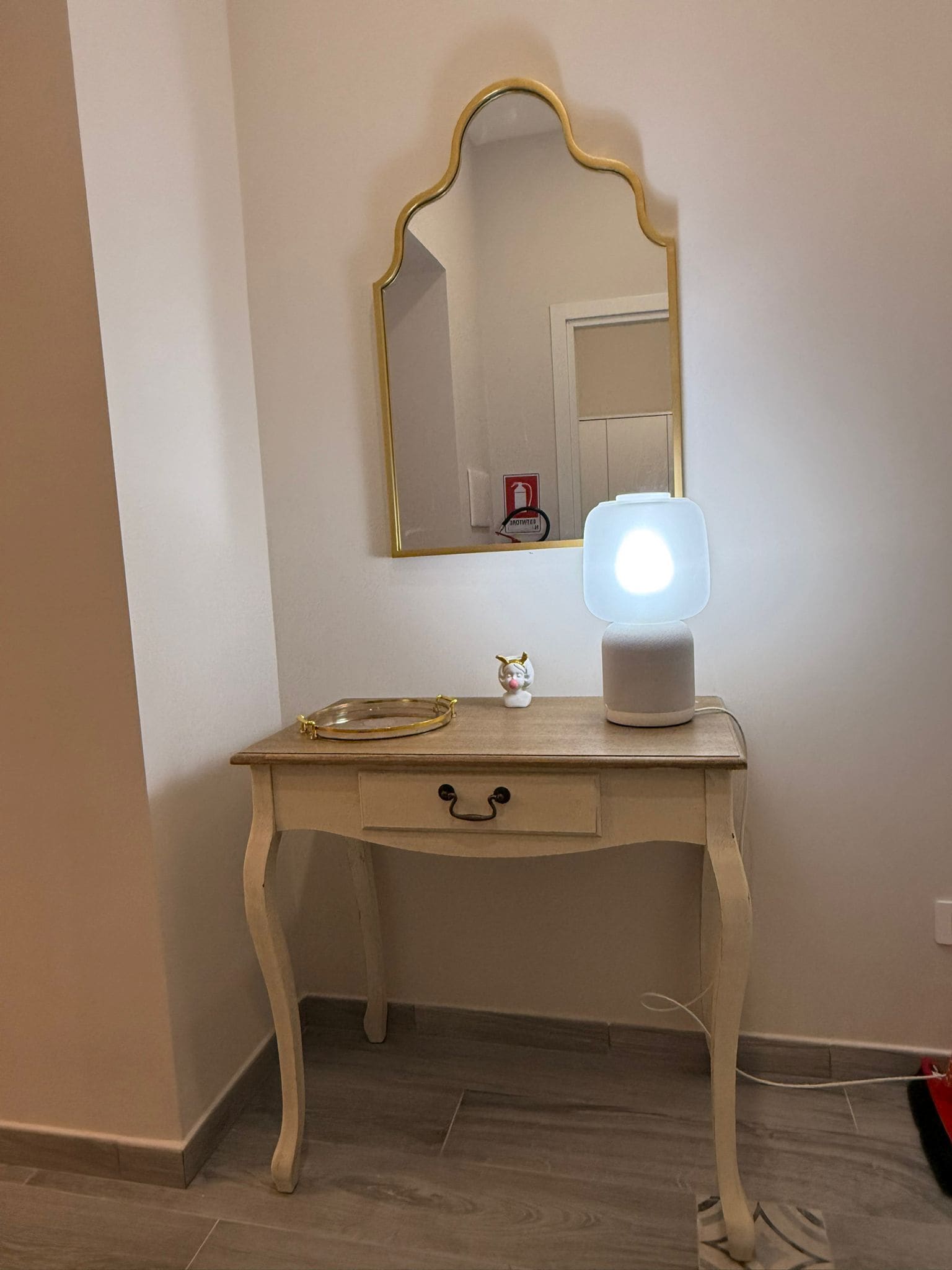 A vanity with a mirror, a light, and a small decorative item.