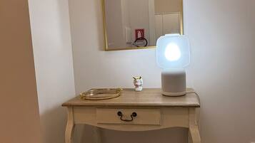 A vanity with a mirror, a light, and a small decorative item.