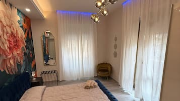 A modern bedroom with a large bed, a mirror, a chair, and a ceiling light fixture.
