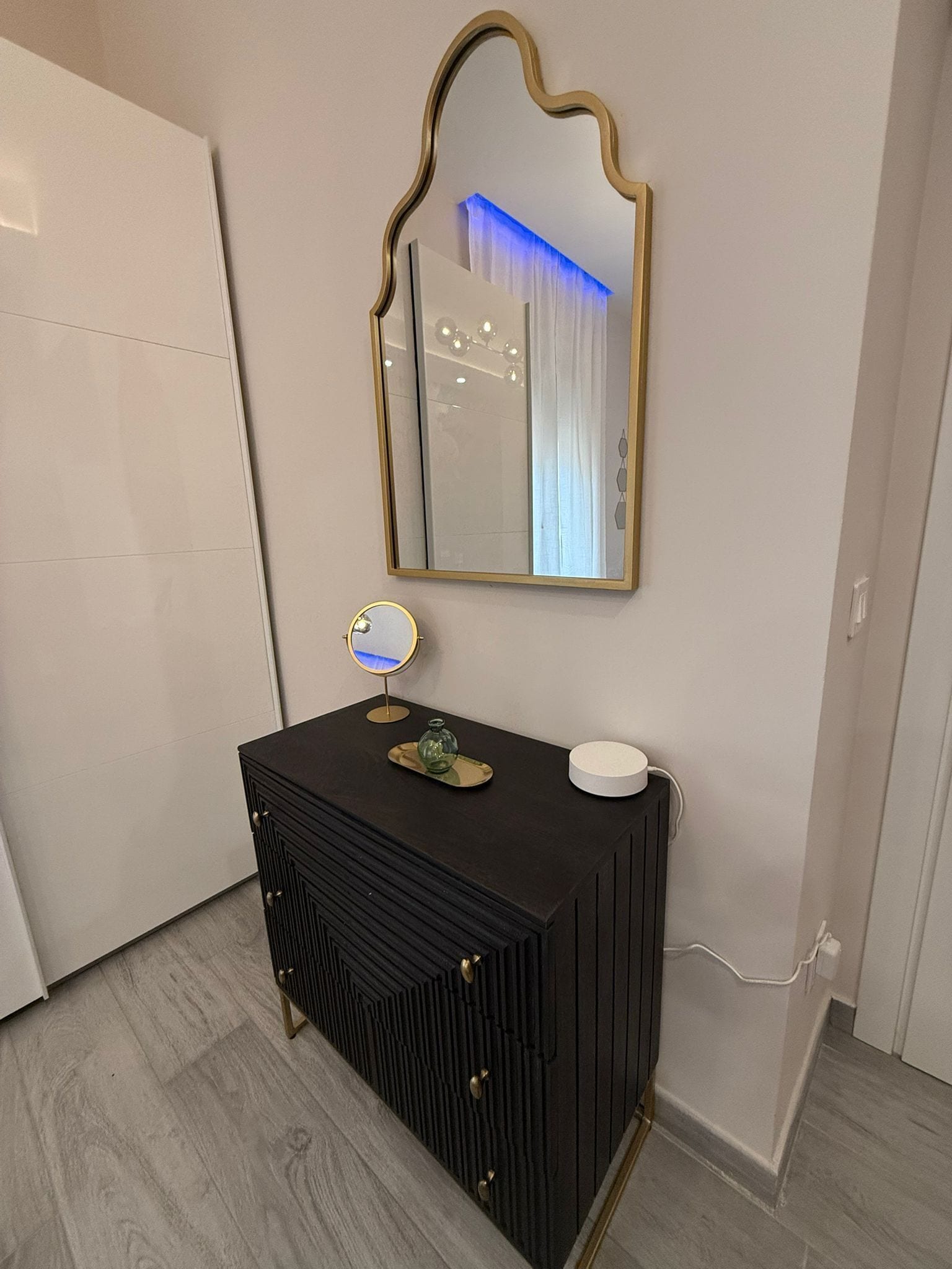 A bathroom with a black vanity, a mirror, and a light fixture.
