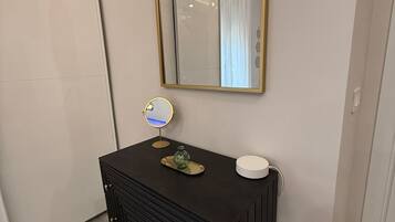A bathroom with a black vanity, a mirror, and a light fixture.