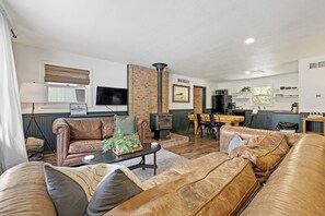 A spacious living room with leather sofas, a fireplace, a dining area, and a kitchen in the background. - The Golden Slipper Cabin (Keystone)