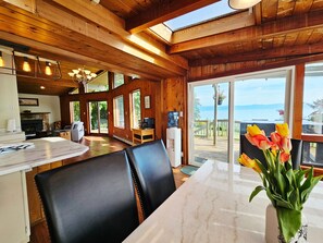 Un intérieur en bois comprenant un coin repas, une cheminée et une vue sur l’extérieur.