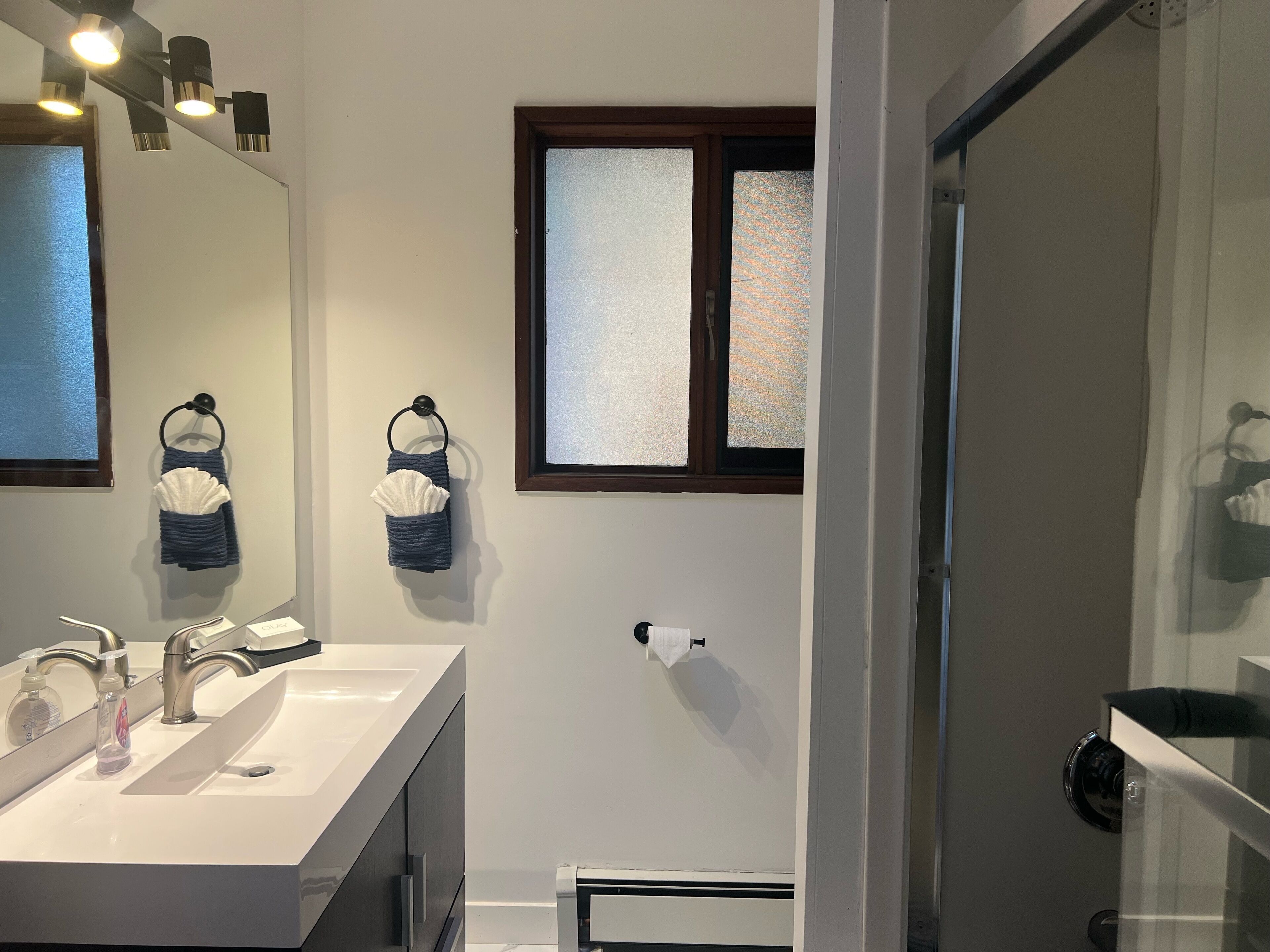 Un baño moderno con lavamanos doble, un espejo grande y una ventana con vidrio esmerilado.