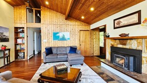 Ein geräumiges Wohnzimmer mit Holzboden, Kamin und einer Couch.