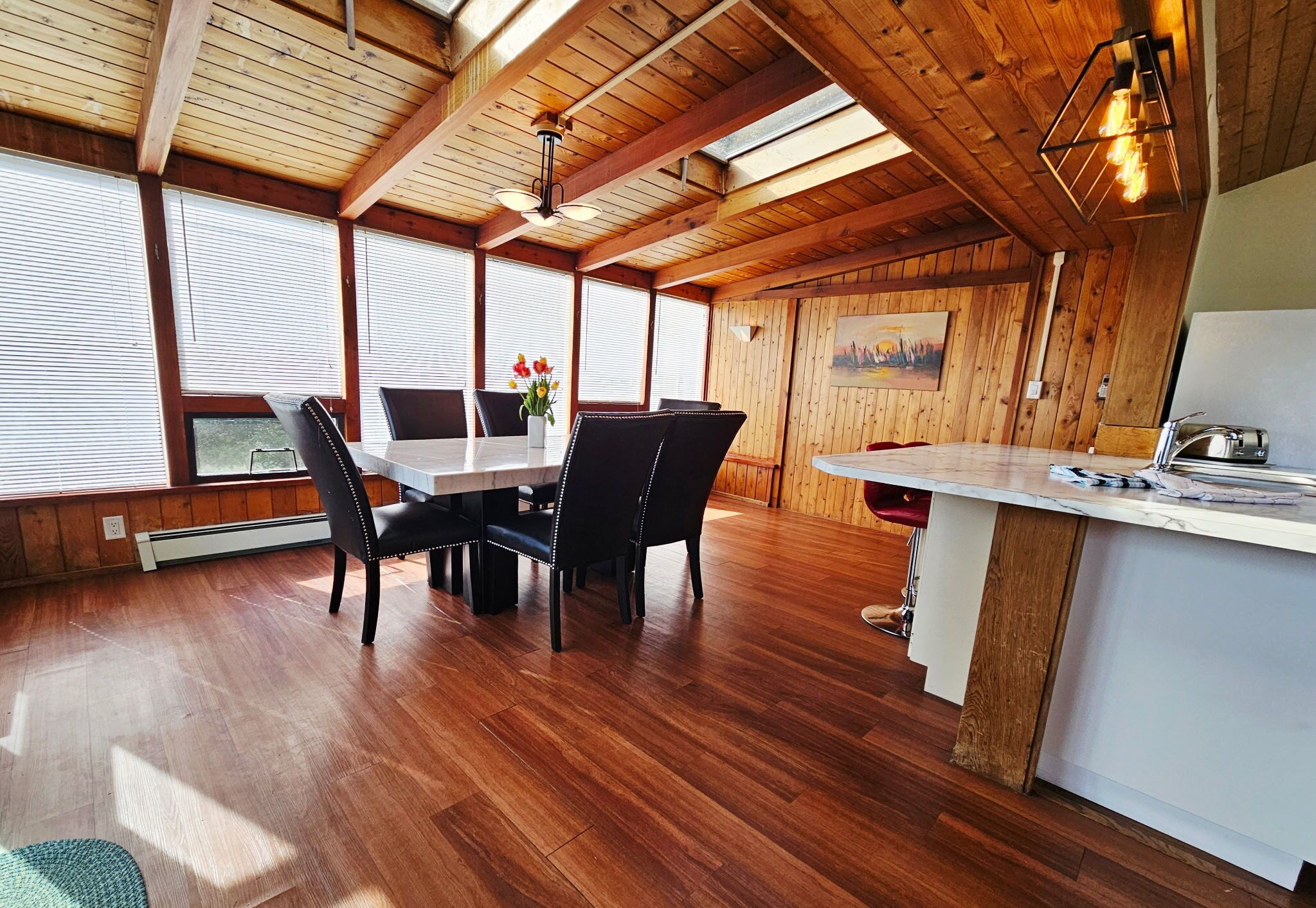 A wooden interior with a dining table, chairs, and a kitchen area.