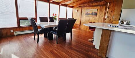 A wooden interior with a dining table, chairs, and a kitchen area.