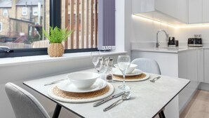 A modern kitchen with white cabinets, a built-in oven, and a window with a view of buildings.