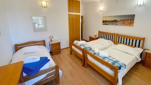 A bedroom with two wooden beds, a wardrobe, bedside tables, and wall-mounted lights. - Villa Mandarin (Carvoeiro)