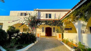 A building with a cobblestone entrance, a red-tiled roof, and a white facade. - Villa Mandarin (Carvoeiro)