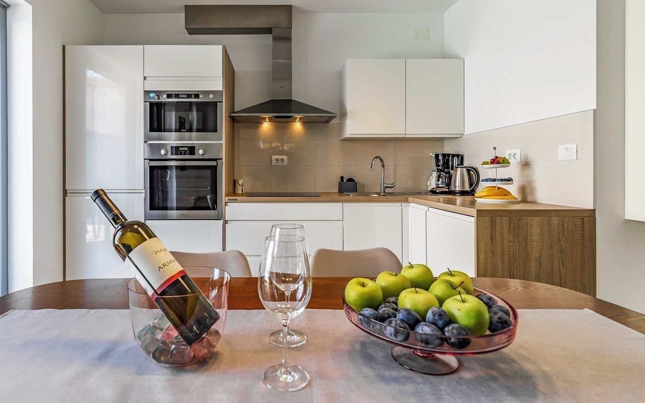 A modern kitchen with white cabinets, stainless steel appliances, and a dining area with a table set for two.