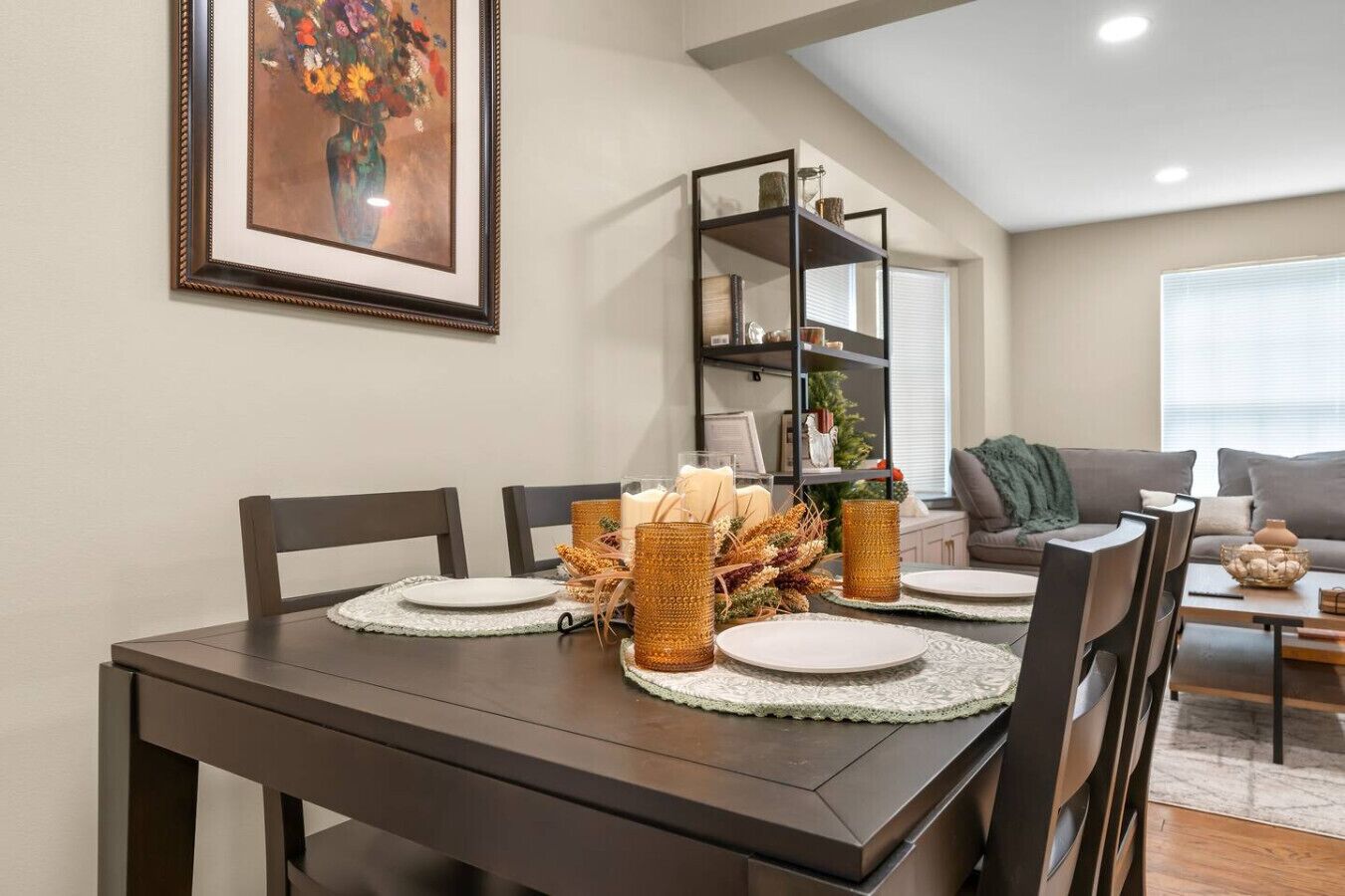 Zona pranzo con un tavolo in legno scuro, quattro sedie e un quadro appeso al muro.