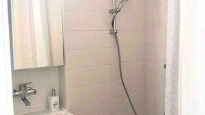 A bathroom with a white sink, mirror, and a shower with a handheld showerhead.