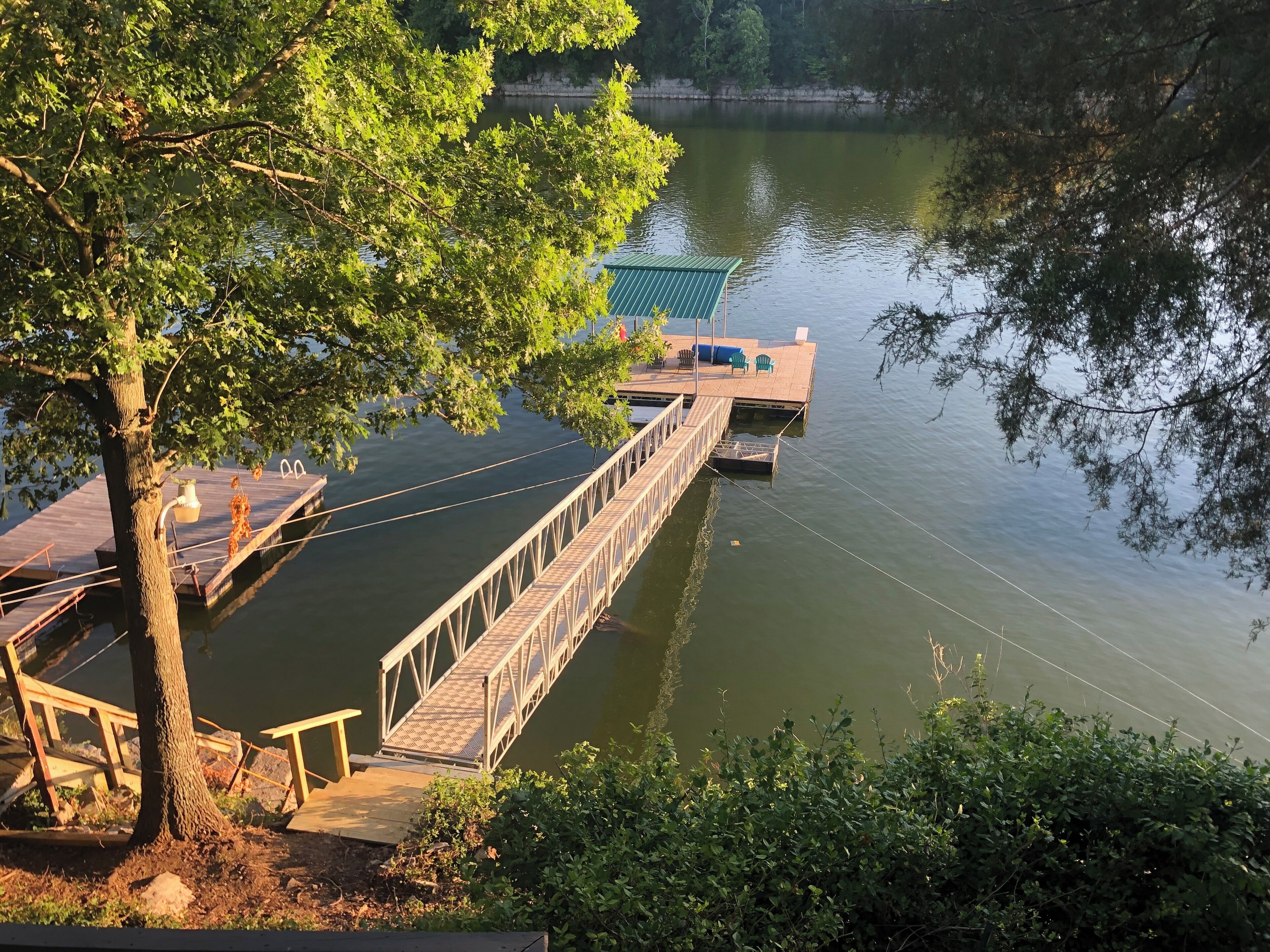 A wooden dock extending over calm water, with a small platform and benches.