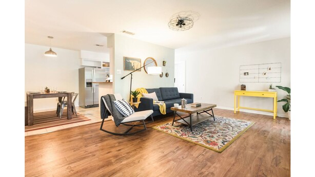 A modern living room with a sofa, a rocking chair, a coffee table, and a yellow side table. - Woodstone Getaway (Austin)
