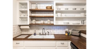A kitchen with white cabinets, a wooden countertop, and a built-in sink. - Woodstone Getaway (Austin)