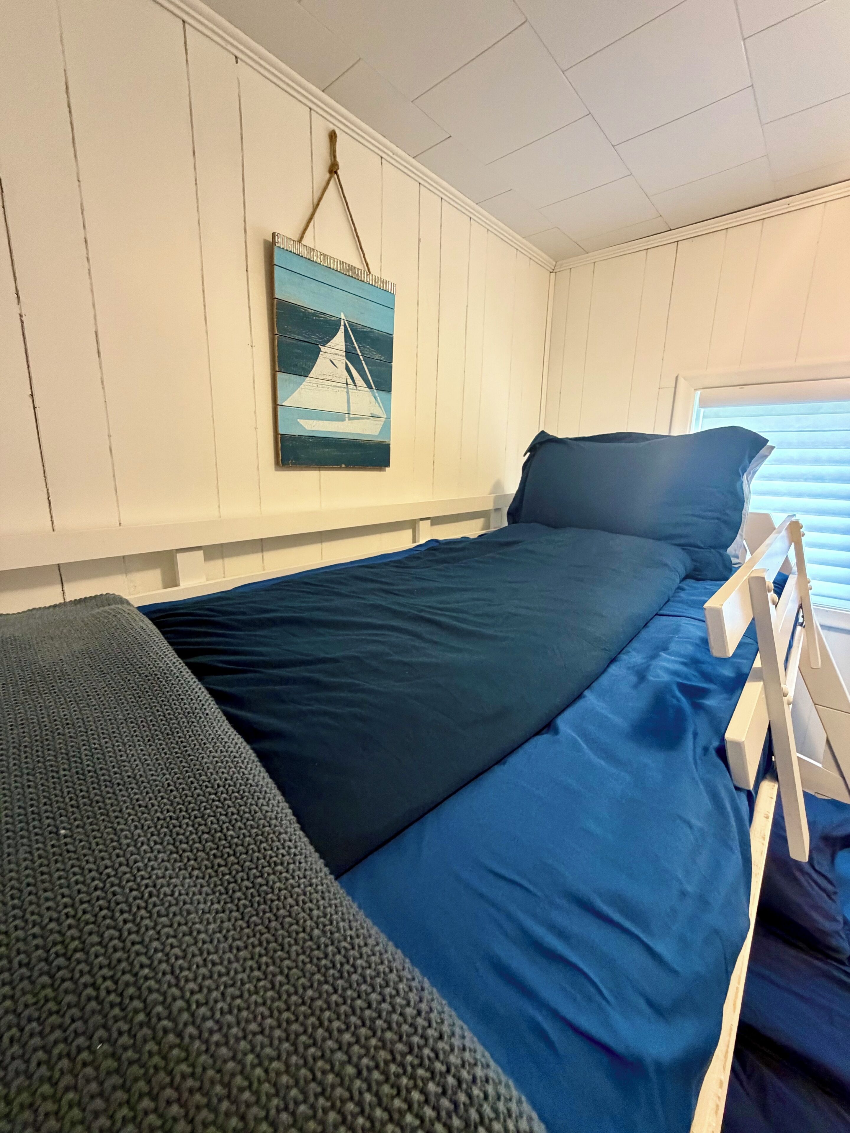 Una habitación con cama, una mesita y un cuadro colgado en la pared.