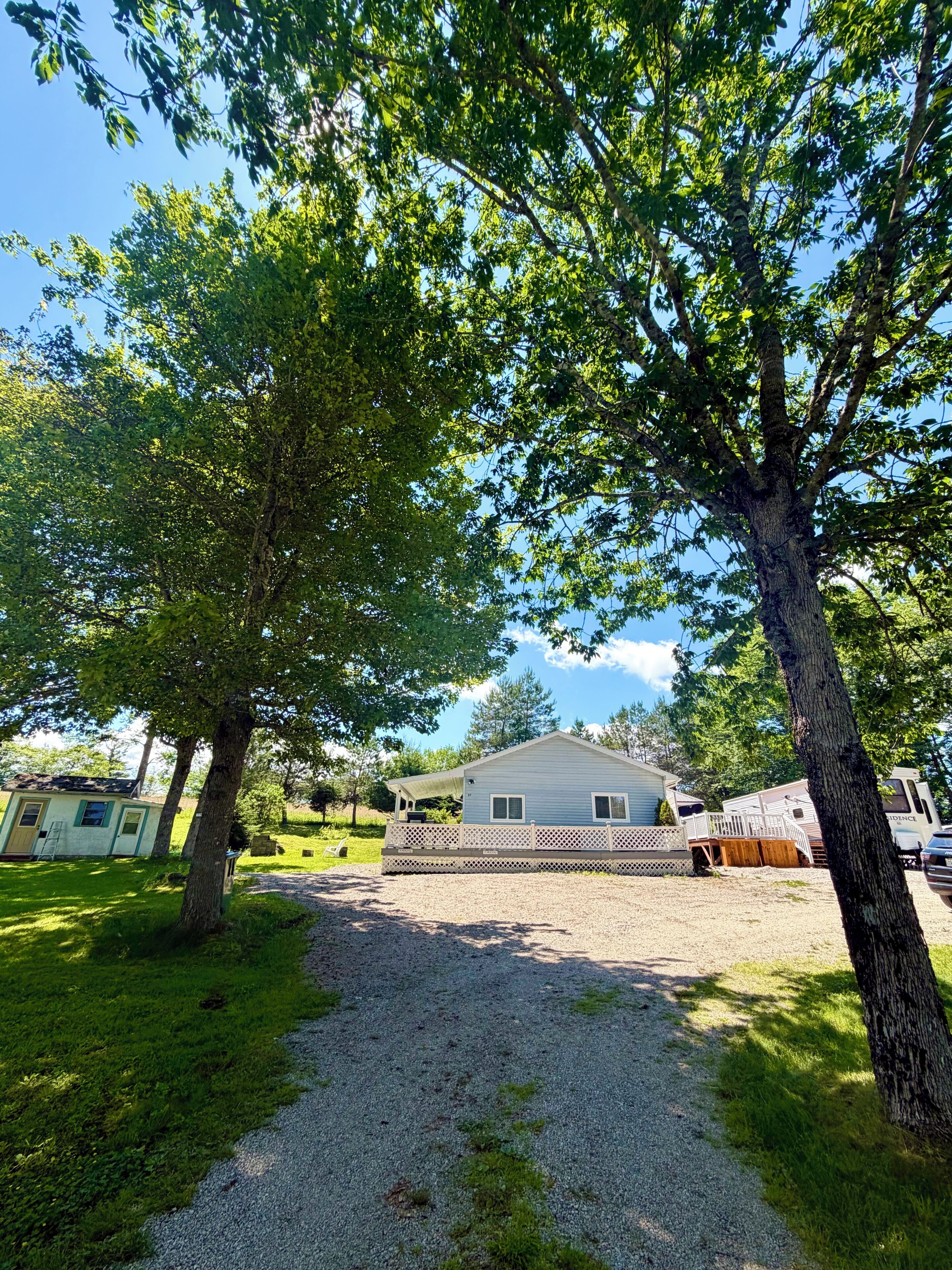 A single-story house with a covered porch, a gravel driveway, and a grassy yard.